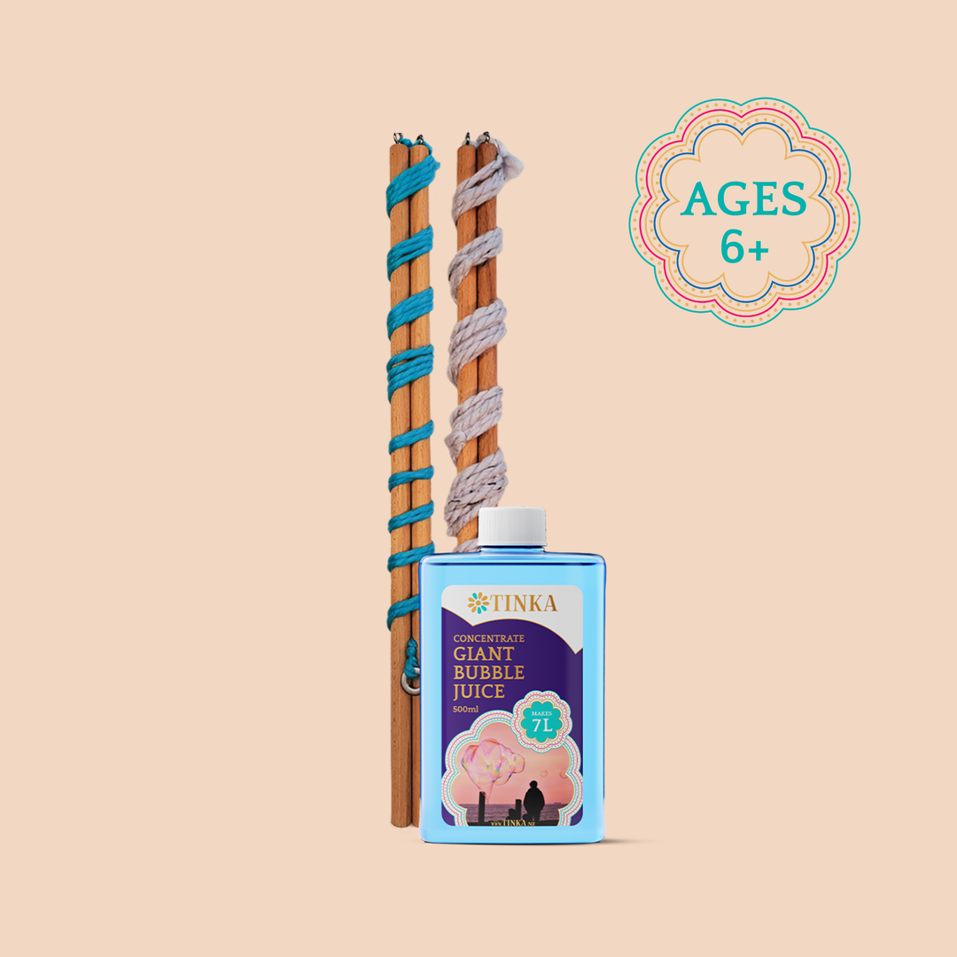 A bottle of Tinka Giant Bubble Juice in blue packaging stands in front of two long wooden wands wrapped with colourful yarn.