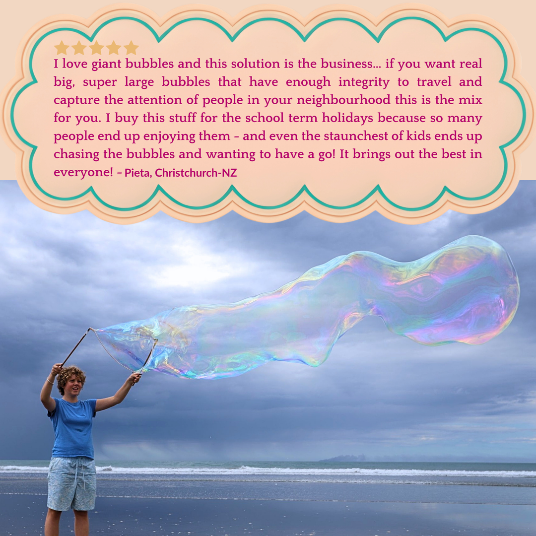 A woman in a blue top creating a long giant bubble, a blue sky behind her and the blue ocean.