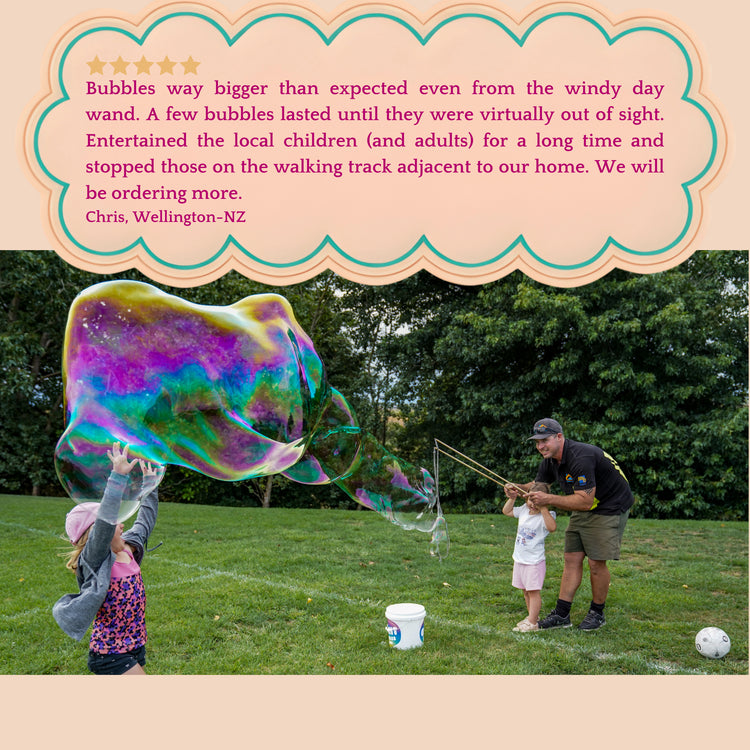 A dad creating giant bubbles on his lawn with his 2 children.