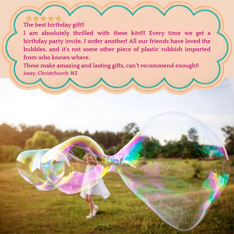 A little girl with a large colourful bubble floating in a grassy outdoor field and a customer review text box at the top with a peach scalloped border.